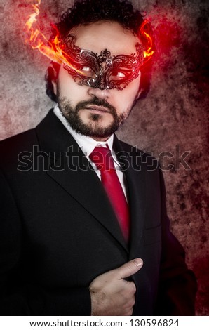 concept evil man with fiery eyes and Venetian mask wearing black dress