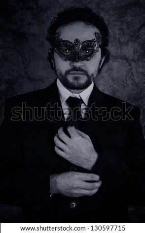 Artistic image of vampire masked mystery man and elegant black suit over vintage background