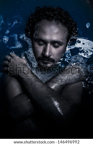 Sexy man deep in blue water, dreaming