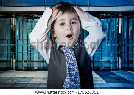 Fun, child dressed businessman with hands in his tie and skyscrapers in the background