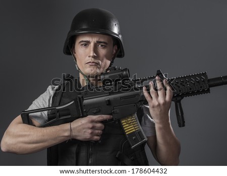 Recreation, paintball sport player wearing protective helmet aiming pistol ,black armor and machine gun