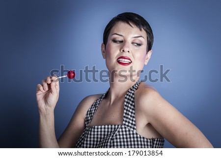 Eat, happy young woman with lollipop  in her mouth on blue background