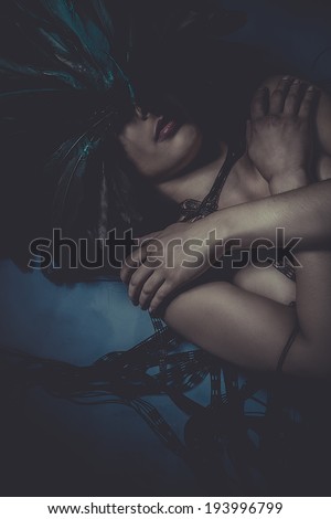 beautiful naked woman lying on the floor with huge feather mask