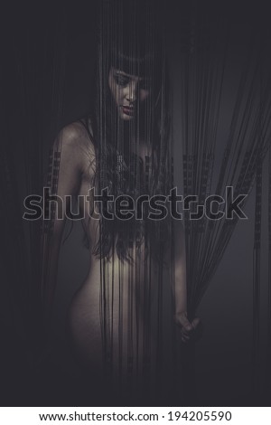 beautiful sensual brunette woman behind a curtain