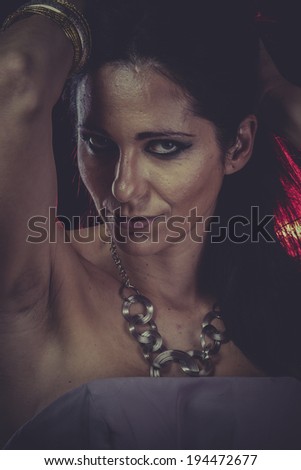 brunette woman with golden jewelry and red light on hair