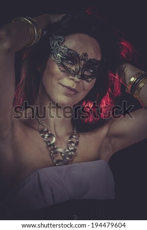 Carnival brunette woman with golden jewelry and red light on hair