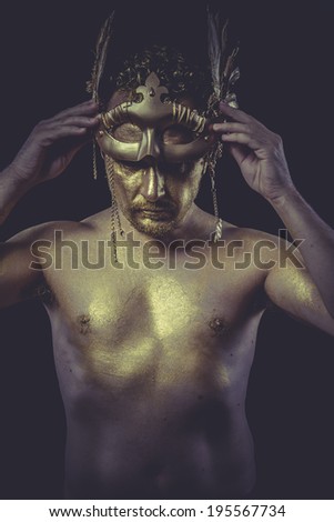 Golden, Man with body painted gold feather mask and steel sword