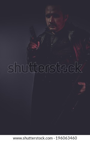 spy portrait of stylish man with long leather jacket, gun armed