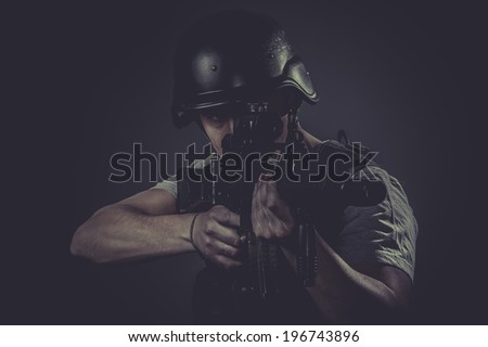 Targeting, paintball sport player wearing protective helmet aiming pistol ,black armor and machine gun
