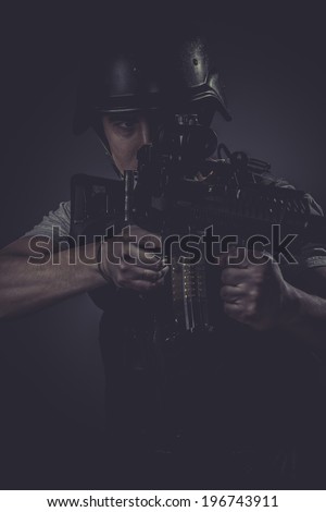 Riot, paintball sport player wearing protective helmet aiming pistol ,black armor and machine gun