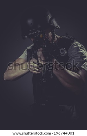 Safety, paintball sport player wearing protective helmet aiming pistol ,black armor and machine gun