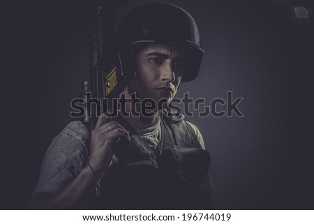 airsoft sport player wearing protective helmet aiming pistol ,black armor and machine gun