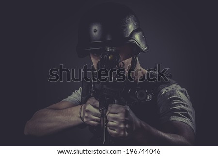 Security, paintball sport player wearing protective helmet aiming pistol ,black armor and machine gun