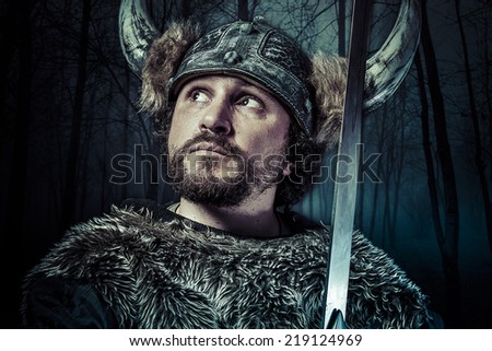 Viking warrior, male dressed in Barbarian style with sword, bearded