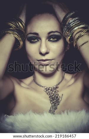 Elegant and sensual woman with golden light, gold and silver jewelry