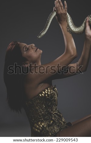Sensual tattooed woman with big snake and iron corset