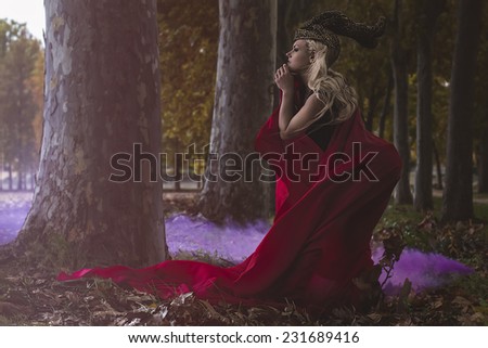 love, beautiful blonde warrior with golden helmet and red cape in the wind