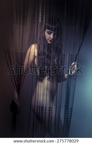 Emotional naked girl behind curtains of black threads