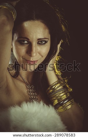 Lady, brunette woman wearing white fur and gold jewelry