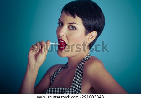 Eat, happy young woman with lollypop  in her mouth on blue background