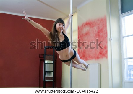 Beautiful girl performing pole dance at gym