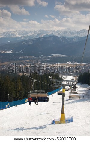 Ski lift with seating bench. Tatra mountains panorama in the background.