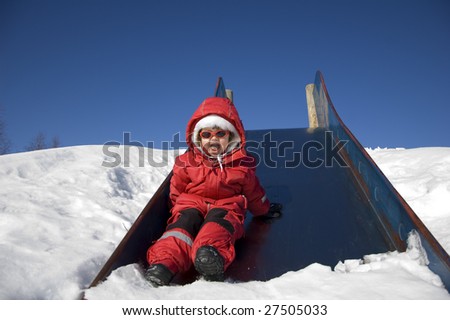 little girl laughing with happiness after a trip down the slide