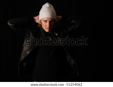 Young man with leather jacket and white hat on a black background