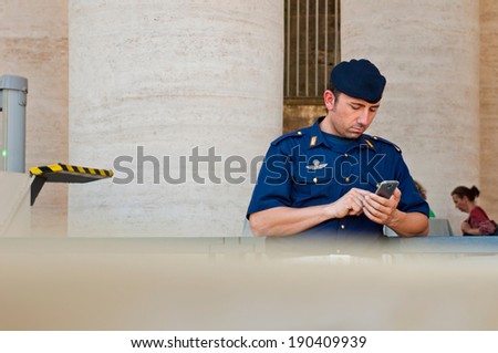 VATICAN CITY - SEPTEMBER 21: unidentified policeman using his mobile phone at St. Peter\'s Basilica security check in Vatican City, Italy on September 21, 2013.