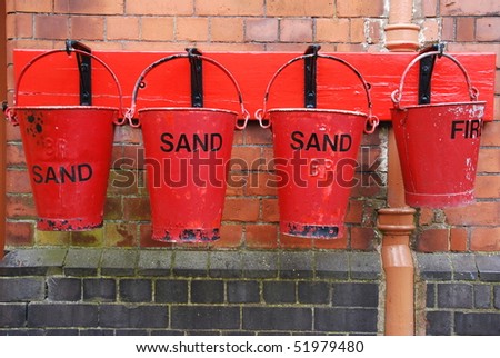 four antique fire buckets on hooks at a train station (brick wall background)