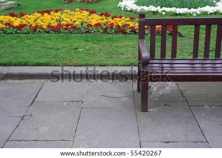 beautiful sidewalk scene with a wooden bench and gorgeous flowers at the background