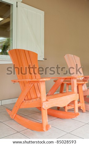 orange and pink wooden rocking chairs on a porch