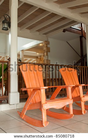 orange wooden rocking chairs on a porch (usual setting on a tropical resort)