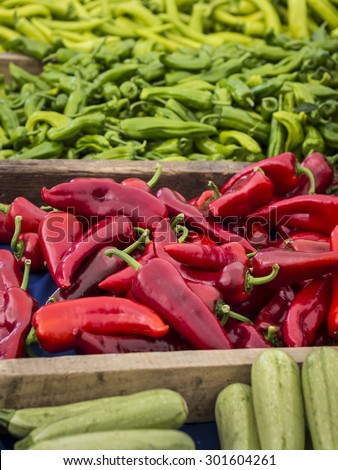 Red chillies in wooden tray with green chillies at the back and cucumbers in front, at a fruit and vegetable market
