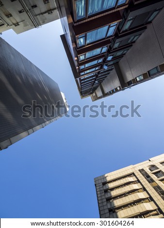 Looking straight up surrounded by modern buildings against a blue sky