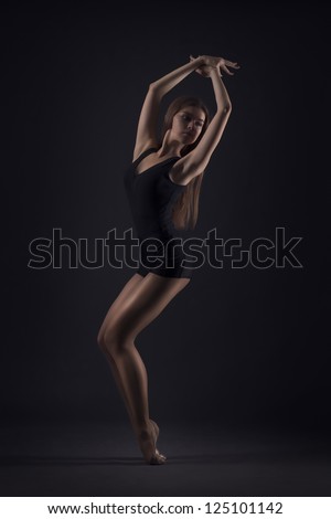 studio shoot of cute woman gymnast on dark background