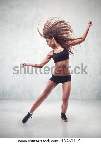young woman dancer with grunge wall background texture dancing