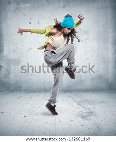 young woman hip hop dancer with grunge wall background texture