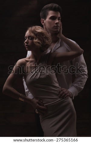 Well-dressed retro couple on dark wooden background