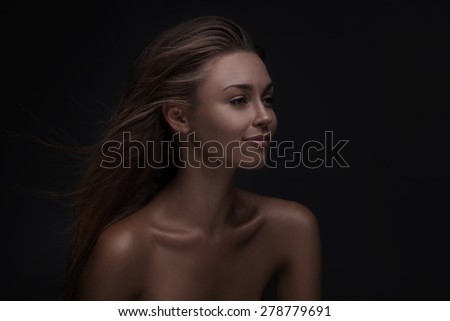 Close-up of beautiful woman face with natural makeup on dark studio background
