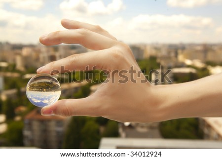 a little glass ball in a hand under the city