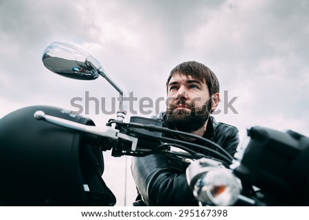 Biker with a beard on his motorcycle in the leather jacket
