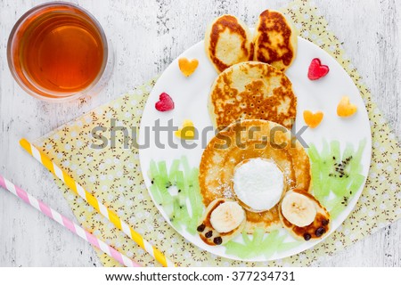 Easter funny bunny pancakes with fruit. Creative breakfast for kids of pancakes, kiwi, banana, apple and juice on a white background top view