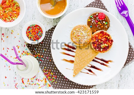 Ice cream pancake with chocolate, jam, peanut butter, colorful sugar. Funny breakfast for kids top view