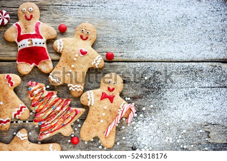 Christmas homemade gingerbread man and christmas tree cookies on snowy wooden table. Traditional cookies with icing and candy cane Christmas gift for kids