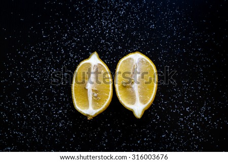 Two halves lemon on a black table with sugar