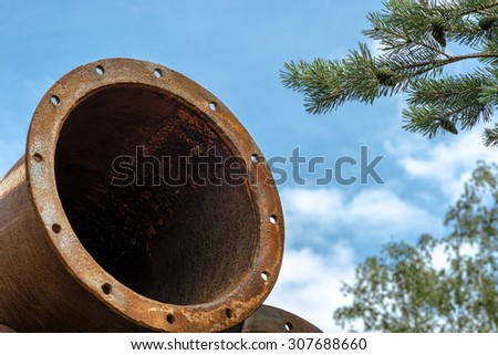 Rusted industrial steel pipes on the tree and blue sky background.