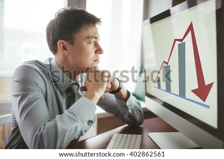 Frustrated stressed shocked business man with financial market chart graphic going down on grey office wall background. Poor economy concept. Face expression, emotion, reaction