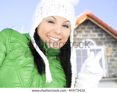 woman in winter clothes pointing new house