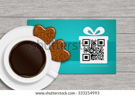 christmas discount coupons with qr code and cup of coffee lying on wooden desk. qr code is designed by author.